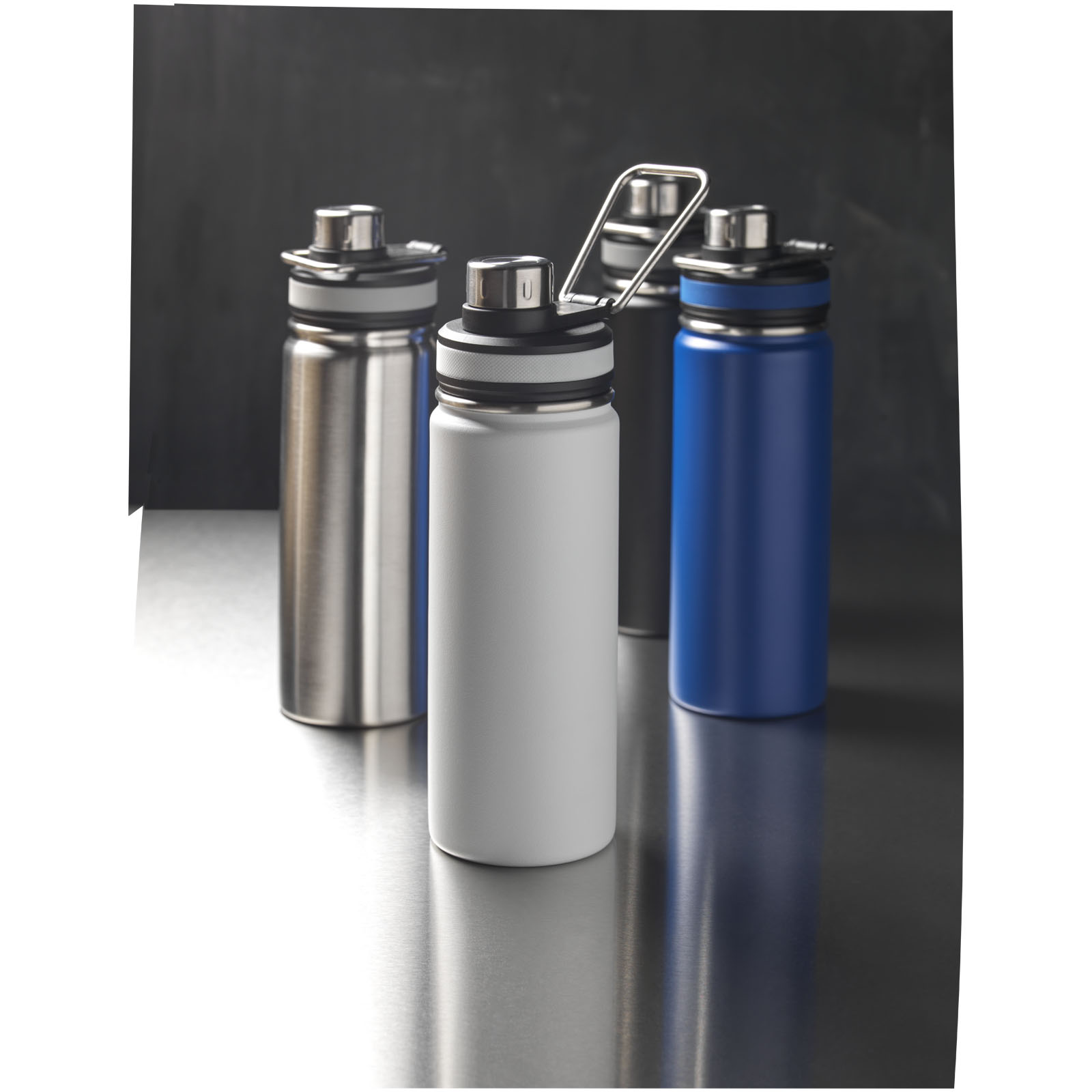 Drei Edelstahl-Trinkflaschen in Silber, Grau und Blau auf dunklem Hintergrund.